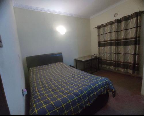 a bedroom with a bed with a blue plaid blanket at 2 br own compound furnished hse in Nairagie Ngare