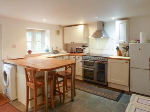 a kitchen with a table and a stove and a refrigerator at Bridge Cottage in Mitchel Troy