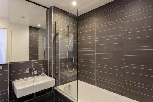 a bathroom with a shower and a sink and a tub at 2 Bed/2 Bath Penthouse With Amazing Views in London