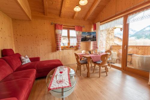 a living room with a red couch and a table at Ferienwohnungen Weiler in Oberstdorf