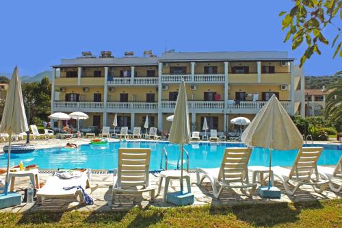 a hotel with chairs and umbrellas in front of a pool at Tzilios Studios in Acharavi