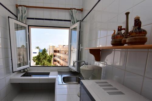 una pequeña cocina con fregadero y ventana en Copacabana 27, en Es Pujols