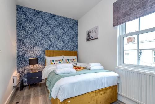 Schlafzimmer mit einem Bett mit blauer Wand in der Unterkunft The Cotswold Woodland in Cheltenham