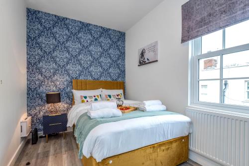 a bedroom with a bed with a blue wall at The Cotswold Woodland by Fortuna Property Portfolio in Cheltenham