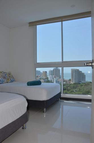 a bedroom with two beds and a large window at Tom Ocean Club con vista al mar piso 15 bello horizonte santa marta carrera 3 #110-55 bello orizonte santa marta in Gaira