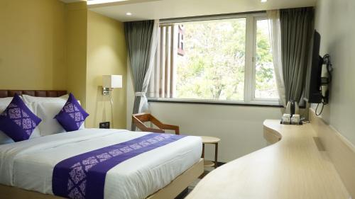 a hotel room with a bed and a window at Purple Beds by VITS - Dwarkesh, Surat in Salabatpura