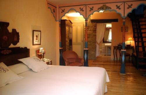 a bedroom with a white bed and a living room at Hospedería Señorío de Briñas in Briñas