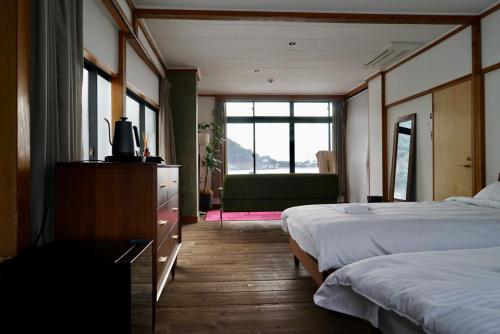 a hotel room with two beds and a window at Tagore Harbor Hostel in Numazu