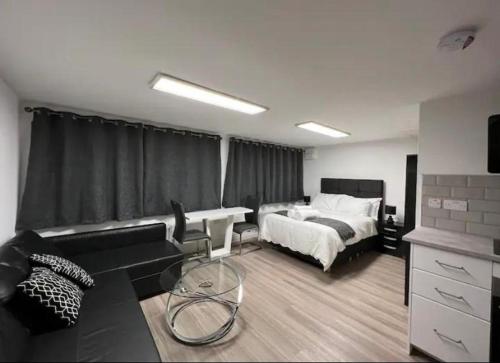 Inviting 1-Bed Studio in Manchester & feel at home في مانشستر: غرفة نوم مع سرير وغرفة معيشة مع أريكة