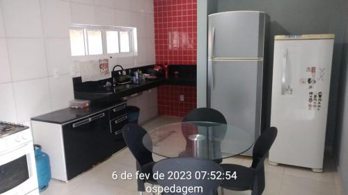 uma cozinha com uma mesa de vidro e um frigorífico em Lar Jampa Beach em Cabedelo