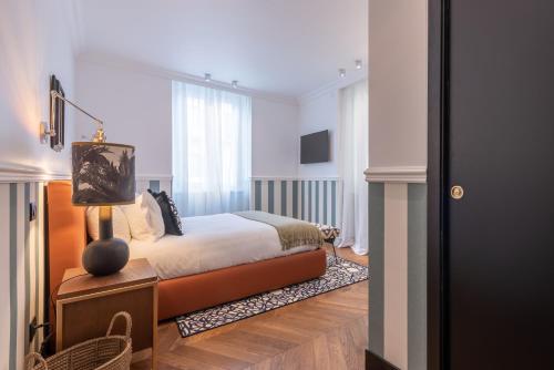 a bedroom with a bed and a table with a lamp at DH Rooms Spiga in Milan