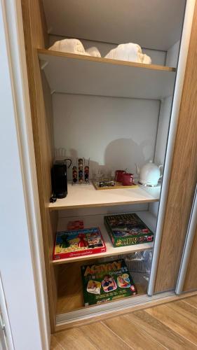 a cupboard with some food and books in it at Franco Apartments in Kežmarok