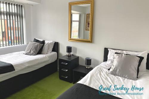 a bedroom with two beds and a mirror at Great Sankey Serviced Accommodation in Warrington