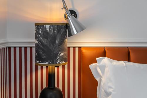 a lamp in a hotel room next to a bed at DH Rooms Spiga in Milan