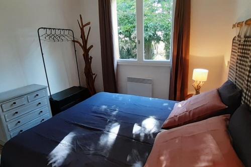 Un dormitorio con una cama azul y una ventana en Magnifique coin de mas avec piscine privative, en Meynes