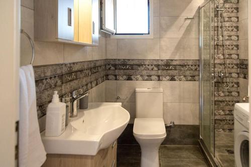 ein Bad mit einem Waschbecken, einem WC und einem Fenster in der Unterkunft Evita home karavados in Karavádhos