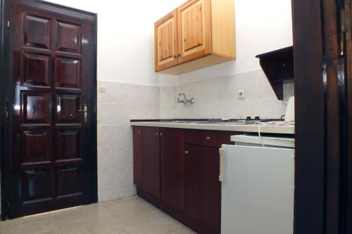 a kitchen with wooden cabinets and a white refrigerator at Tzilios Studios in Acharavi