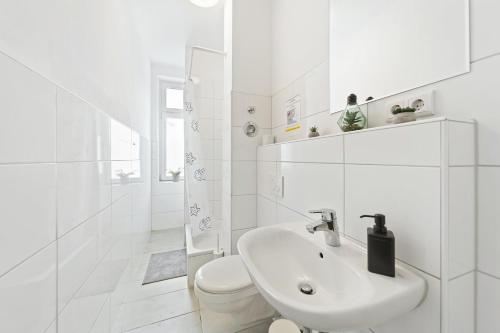 a white bathroom with a sink and a toilet at Gemütliche Apartments im Herzen von Halle in Halle an der Saale