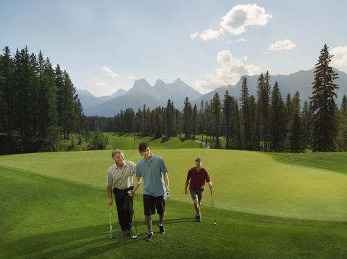 a group of three men walking on a golf course at Falcon Crest Lodge by CLIQUE in Canmore