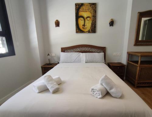 1 dormitorio con 1 cama blanca grande y toallas. en Apartamento Alfareria de Triana - Kainga Homes, en Sevilla