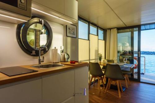 uma cozinha com um lavatório e uma mesa com uma sala de jantar em Hausboot Fjord POLARIS mit Biosauna in Barth em Barth