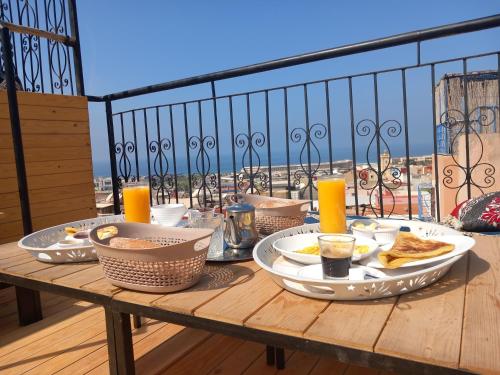 una mesa con platos de comida en el balcón en Santacruz Hostel, en Tamraght Ouzdar