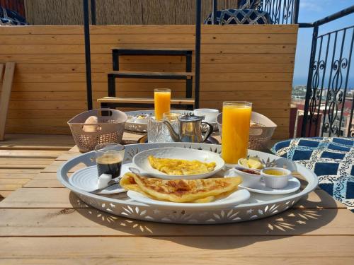 een dienblad met ontbijtproducten op een tafel met sinaasappelsap bij Santacruz Hostel in Tamraght Ouzdar