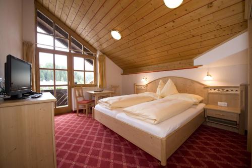 ein Schlafzimmer mit einem Bett und einem TV in einem Zimmer in der Unterkunft Hotel Bischofsmütze in Filzmoos