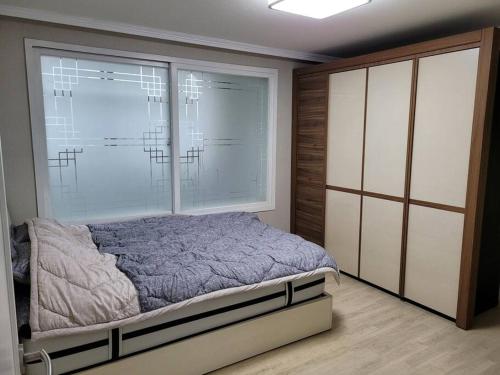 - une chambre avec un lit et une grande fenêtre dans l'établissement SinNaMu Family House, à Suwon