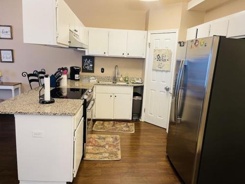 eine Küche mit weißen Schränken und einem Kühlschrank aus Edelstahl in der Unterkunft Eclectic 3 bedroom townhouse with back terrace in Tallahassee