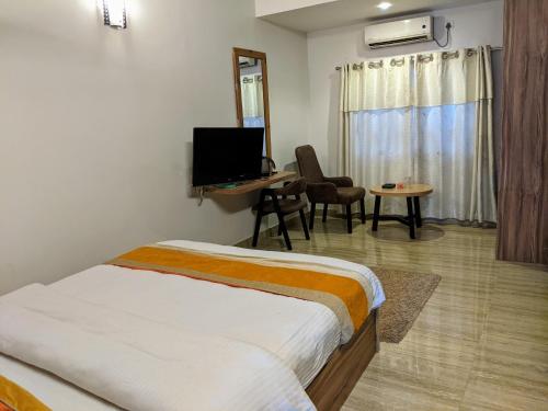 um quarto com uma cama, uma secretária e uma televisão em Gantavya Resort em Pokhara