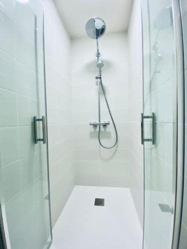 une salle de bain avec une douche avec une porte vitrée dans l'établissement *Bleu Saphir* centre de Vichy, à Vichy