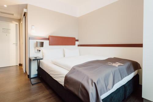 a bedroom with a large white bed and a table at Hotel Kaiserhof in Münster