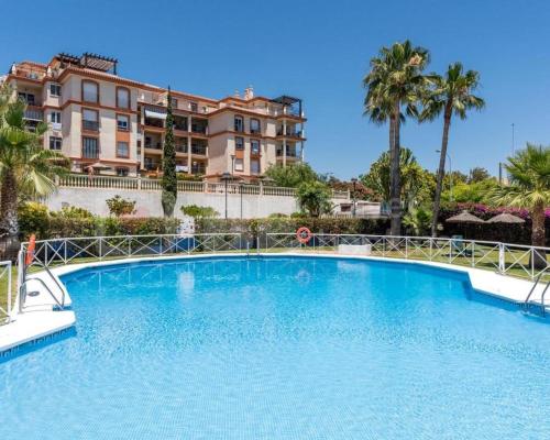a large blue swimming pool in front of a building at 2BDR Sunny apartment with pool and private parking in Benalmádena in Benalmádena