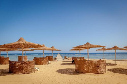 a beach with straw umbrellas and chairs and the ocean at Silver Beach Boutique Hotel in Quseir