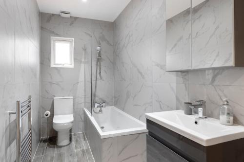 Baño blanco con lavabo y aseo en Star London Station Road 3-Bed Oasis with Garden en The Hyde