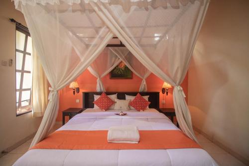 - une chambre avec un lit à baldaquin dans l'établissement Giri Sari Guest House Pemuteran Bali, à Pemuteran