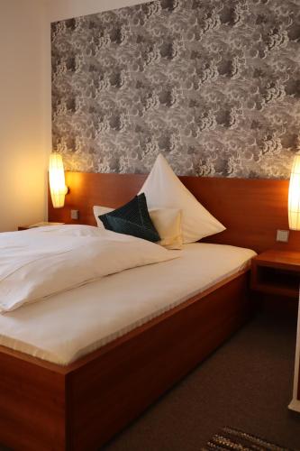 een slaapkamer met een bed met witte lakens en behang bij Thuns Dorfkrug in Werdohl