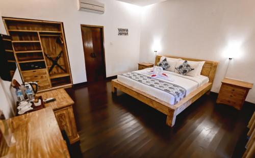 a bedroom with a large bed and a wooden floor at Royal Regantris Villa Karang in Gili Air