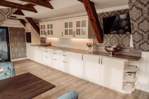 a kitchen with white cabinets and a tv on the wall at AnaCapri Gästehaus Lugano in Ueckermünde