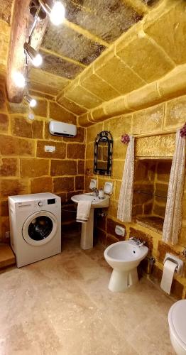 a stone bathroom with a sink and a washing machine at Il Mithna farmhouse with indoor heated jacuzzi pool in Għarb