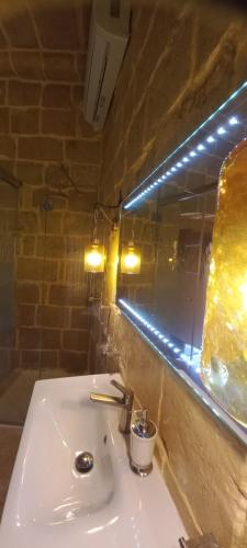 a bathroom with a white sink and a mirror at Il Mithna farmhouse with indoor heated jacuzzi pool in Għarb