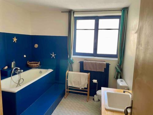 a blue bathroom with a tub and a toilet at La maison du prieuré in Vézénobres