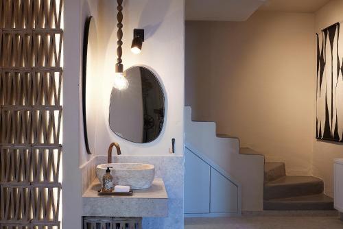 ein Badezimmer mit einem Waschbecken, einem Spiegel und einer Treppe in der Unterkunft Cycladic Villa ERoza in Ioulis