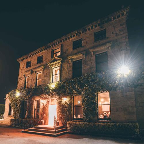 a building with ivy on the side of it at night at Healds Hall Hotel in Cleckheaton