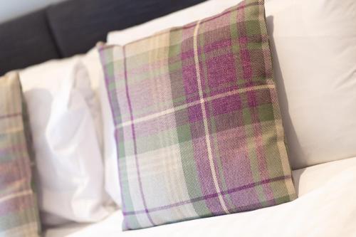 a plaid pillow sitting on top of a bed at Healds Hall Hotel in Cleckheaton