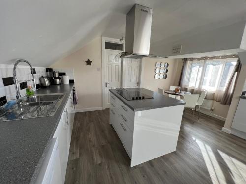 uma cozinha com armários brancos e um balcão preto em Edge of Glastonbury and Street Town Centre, 2BD Apt with Parking em Street