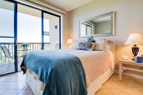 a bedroom with a bed with a mirror and a balcony at Pirates Bay A402 in Fort Walton Beach
