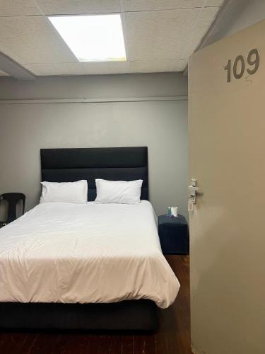 a bed with white sheets and pillows in a room at Stay Inn Lodge Randfontein in Randfontein