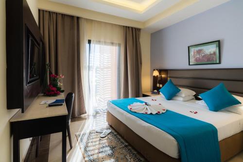 a hotel room with a bed and a desk and a window at Pickalbatros Aqua Fun Club All Inclusive in Marrakech